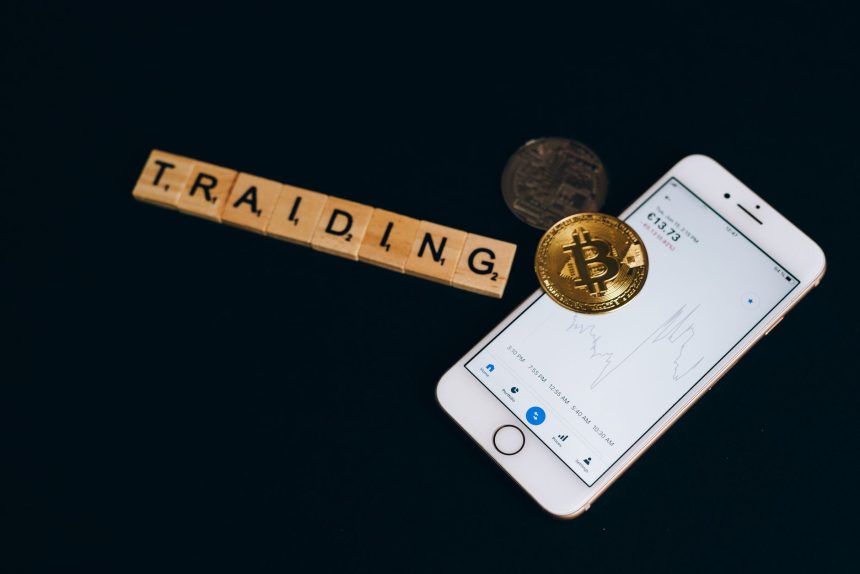 Bitcoin sikkesi, kripto uygulaması açık bir telefon ve harf taşları