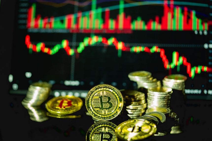Bitcoin ve metal sikke yığınları, arkada kırmızı-yeşil mum grafiği